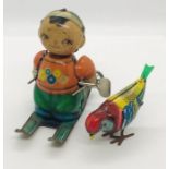 A vintage tinplate clockwork skier and pecking tinplate bird with keys (key for bird in office)