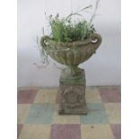 A vintage concrete garden pot on plinth