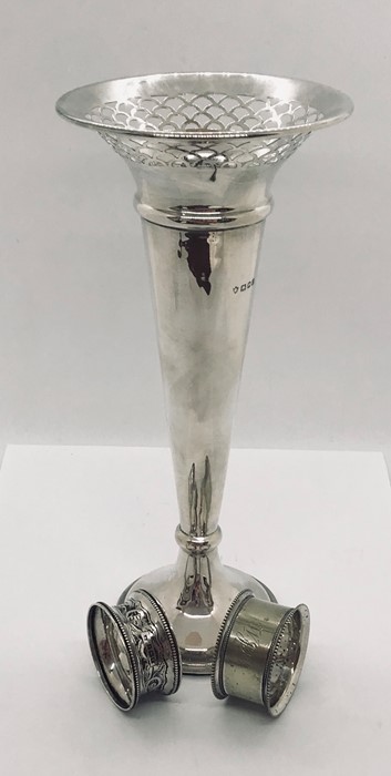 A large silver trumpet vase and two serviette rings.