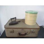 A vintage "airport" suitcase with keys, metal three tier cake tin and an iron on trivet