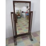 A mahogany cheval mirror with unusual double claw feet to either side, raised decoration and scallop