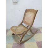 An Edwardian folding rocking chair with cane seat