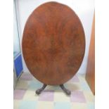 An oval walnut veneer tip up breakfast table