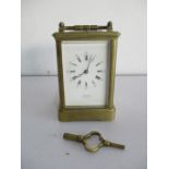 A brass carriage clock with strike repeat movement, the white enamel dial with Roman and Arabic