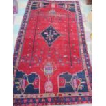 A Eastern hand woven red ground rug