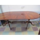 A Regency oval dining table with one extra leaf on two tripod bases- replacement clips
