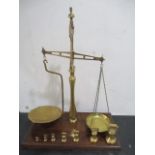 A set of Ibrasco brass beam scales on a mahogany plinth along with a set of bell weights