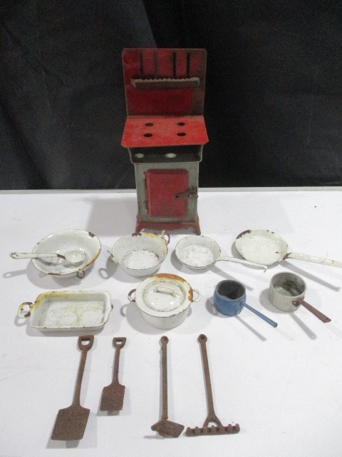 A collection of dolls house items including cooker, enamelled cookware and cast iron garden tools