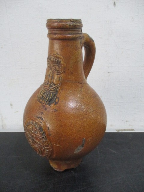 A 17th/18th century Bellarmine jug with bearded mask over armorial- neck repaired- approx 23cm
