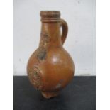 A 17th/18th century Bellarmine jug with bearded mask over armorial- neck repaired- approx 23cm