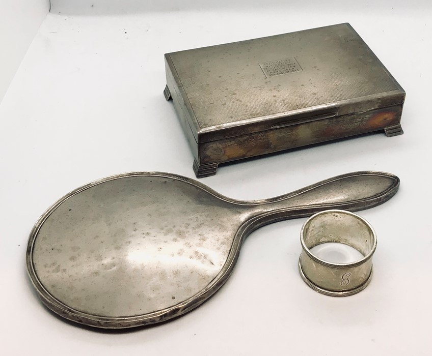 A hallmarked silver cigarette box, silver hand mirror along with a silver serviette ring