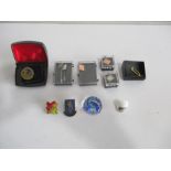 A collection of lapel/badges including two in hallmarked silver, along with a glass paperweight,