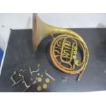 A brass French Horn with mouthpiece and fittings