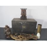 A wooden chest containing brass WWII shell, fireside tools, paraffin stove, storm lamps etc