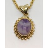 A 9ct gold chain and pendant set with a cabochon stone