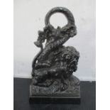 A cast iron doorstop in the form of a lion fighting a serpent