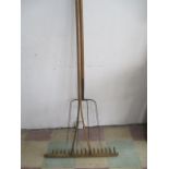 Two large farm tools, a pitchfork along with a rake