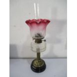 A Victorian oil lamp with twist brass column and cranberry glass shade