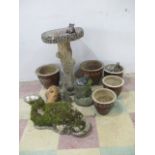 A concrete bird bath, along with other various garden pots and ornaments