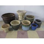 A concrete birdbath along with various ceramic garden pots