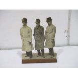 A vintage wooden stand of three men in raincoats