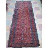 A hand woven red ground rug