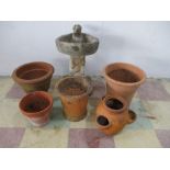 A concrete bird bath along with various terracotta pots