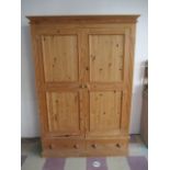 A large pine wardrobe with two drawers under