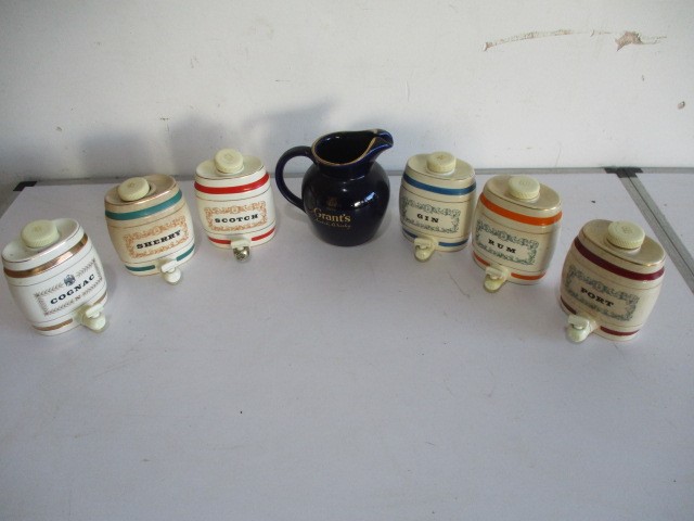 A collection of Wade ceramic sprit barrels, along with a Grant's Scotch Whisky water jug