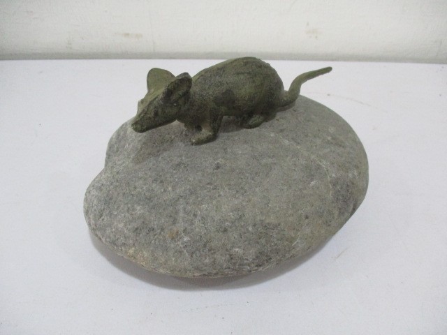 A bronze figure of a mouse crouched on a stone