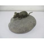 A bronze figure of a mouse crouched on a stone