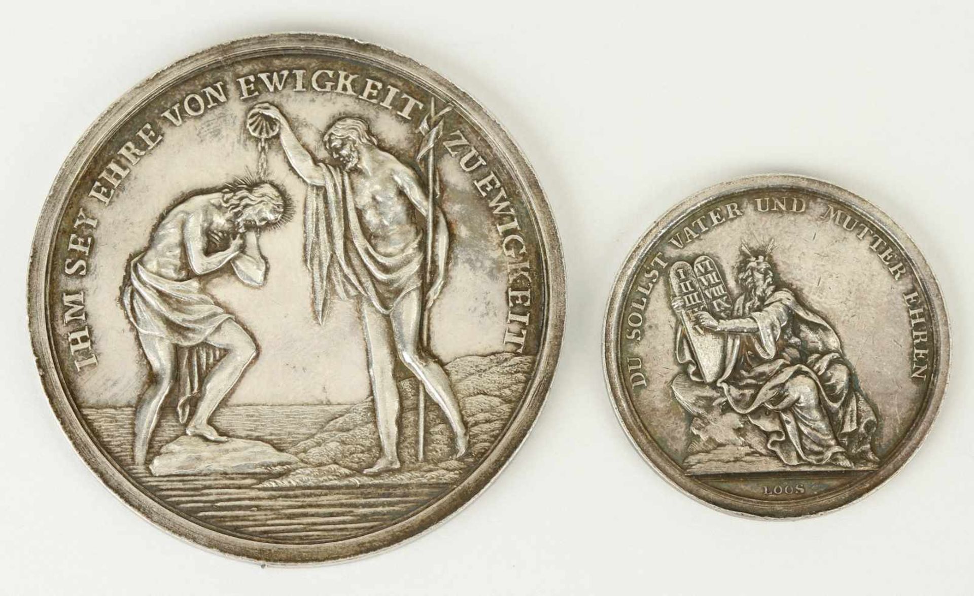 Eine Taufmedaille und eine Medaille mit biblischer Szene