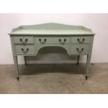 A painted knee hole ladies dressing table on tapered legs and castors with brass handles. W:122cm