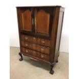 A 19th century mahogany cabinet. Two cupboard doors over three sculpted drawer fronts raised on ball