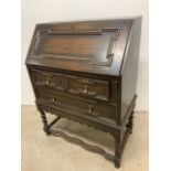 An inlaid oak bureau with brass handles on barley twist legs-with key