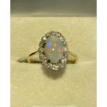 An unmarked yellow and white metal Opal and diamond dress ring. Central oval cabochon opal with