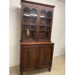 A Victorian mahogany two piece glazed display bookcase over two door cupboard with key. W:106cm x