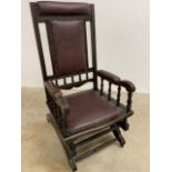 A vintage American rocking chair on metal castors with burgundy leather upholstery and studwork