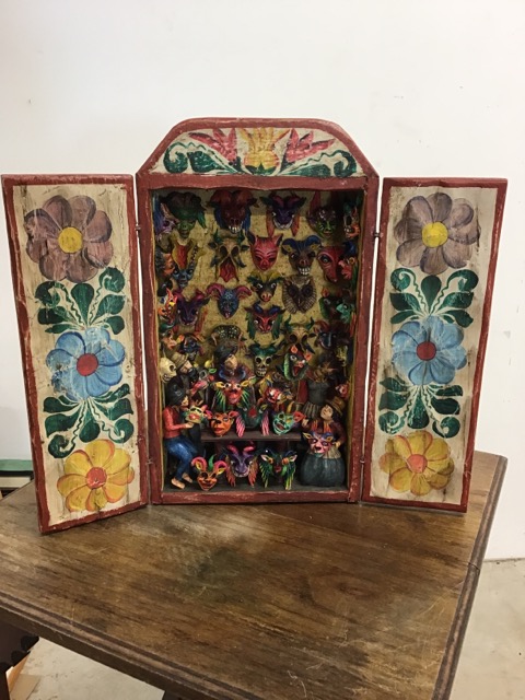 A South American painted plaster sculpture in a painted wooden box of The Mask Seller of the Dead.