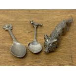 A white metal fox with two fox related spoons.