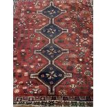 A Persian carpet, red field and blue central medallions with floral symbols. W:205cm x D:cm x H: