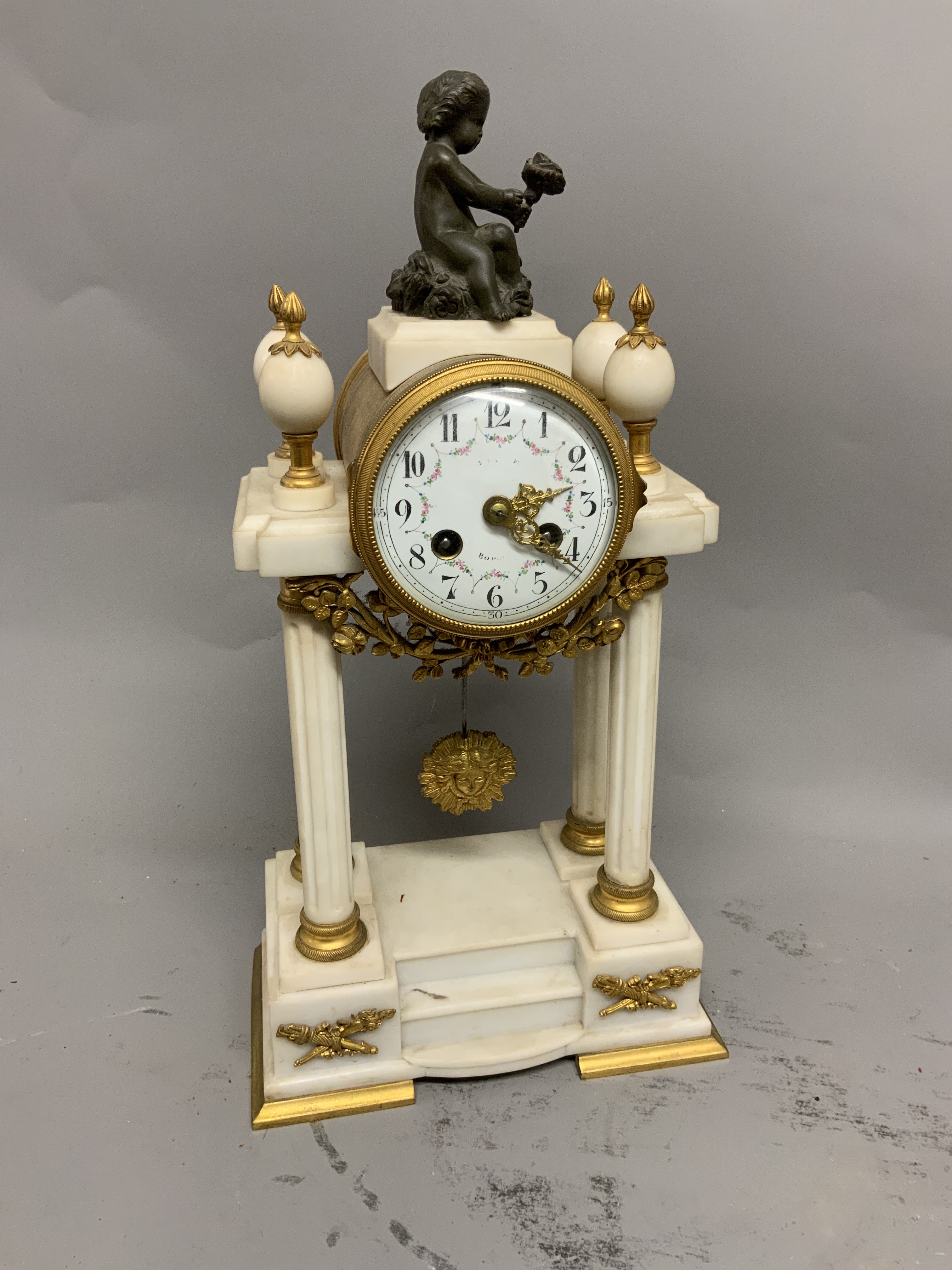 A French marble gilt metal pedestal mantle clock. Enamel face with Arabic markers and floral