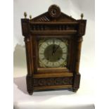 A late 19th century German chiming Carved oak bracket clock. Pineapple finials above brass dial with