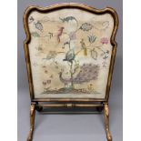 A decorative walnut fire screen with needlework of peacock, parrots and flora and fauna.W:56cm x