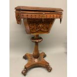 A rosewood sewing table on brass castors with a turned and carved decorative centre pedestal a
