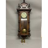A large mahogany Vienna style wall clock. Enamel face with Roman numeral markers. 136cm(h)