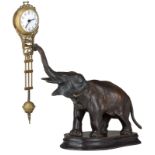 A fine patinated bronze clock on a wooden base, the clock shaped like an elephant holding a brass ly