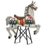 A polychrome painted carousel horse, with glass and silver foil inlay, mounted on a later period wro