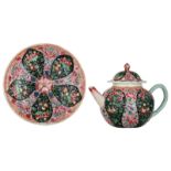 A Chinese famille rose black ground relief decorated teapot and saucer with floral decoration, Yongz