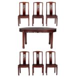 A fine Chinese rosewood extendable dining table with a set of six matching chairs, decorated with op